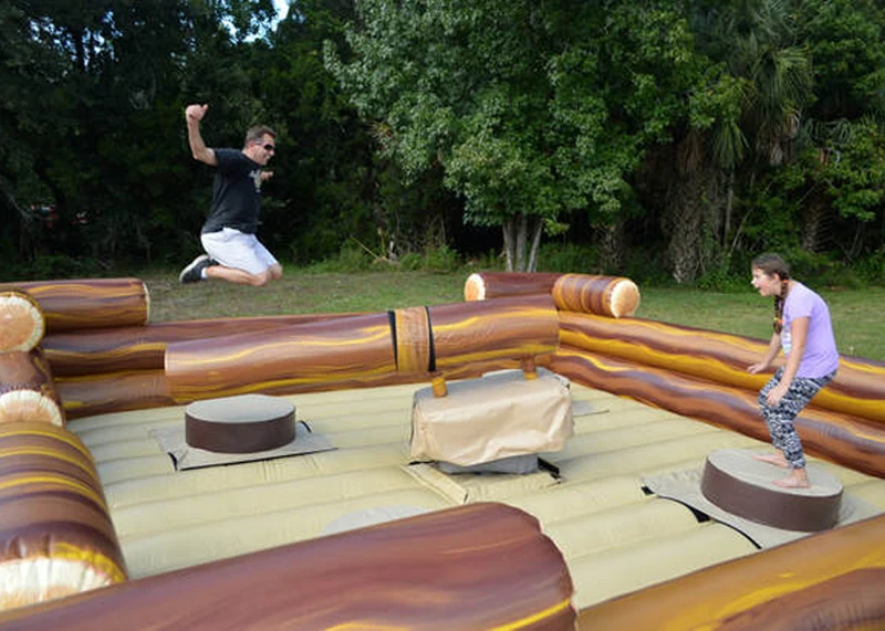 Four players dodging spinning log arms on the Four Man Log Slammer mechanical ride rental and attraction rental