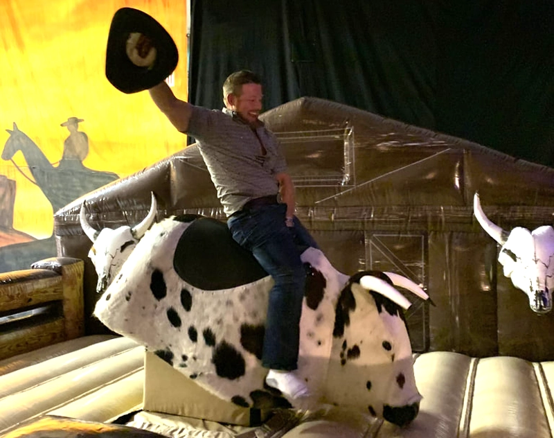 Cowgirl riding a Florida mechanical bull rental, mechanical ride rental and attraction rental at an outdoor event